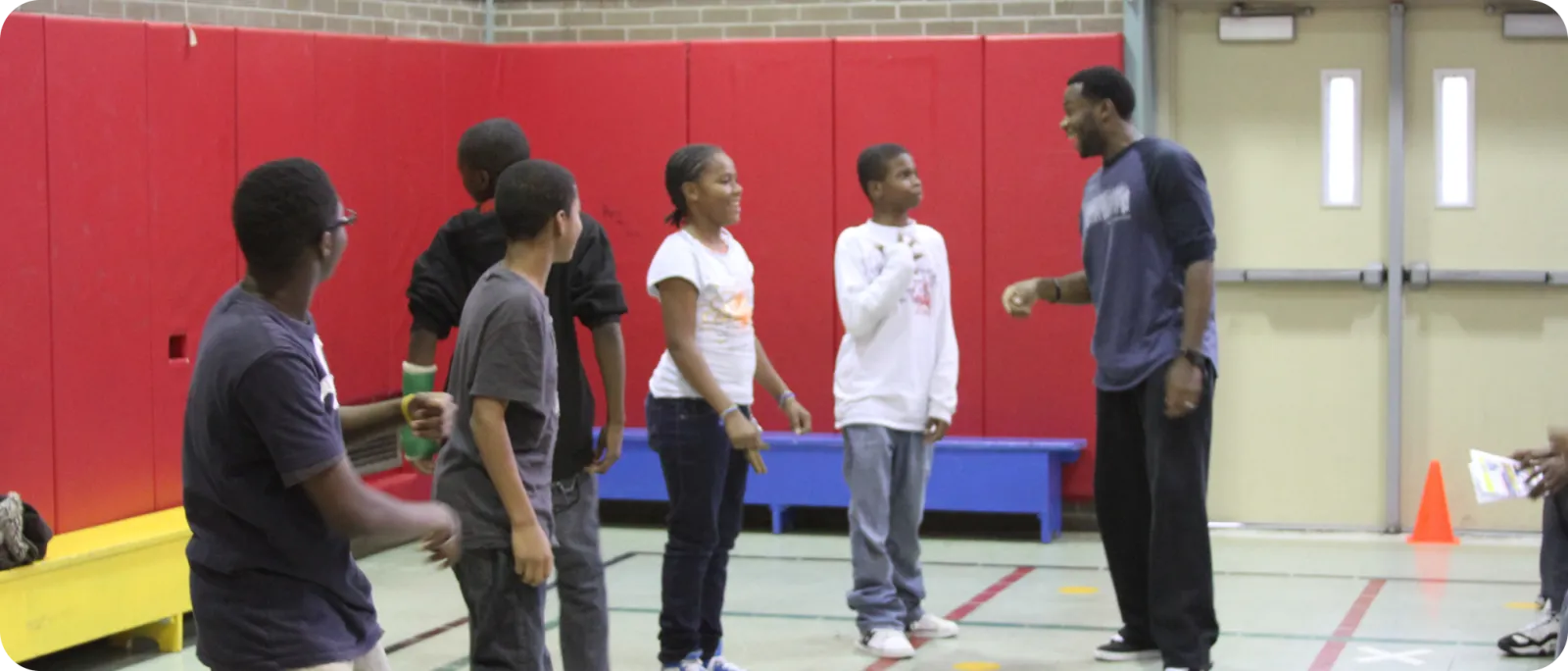 Deo Mwano leading an activity with middle-school students in a gym